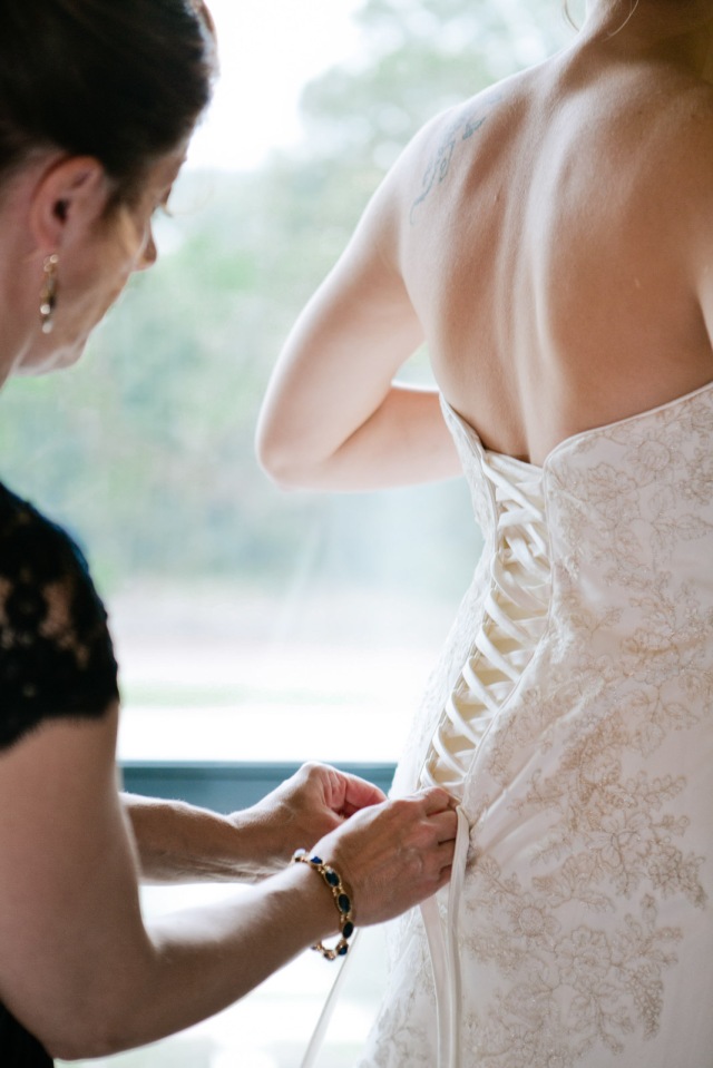 The mother of the bride laces up the brides wedding dress